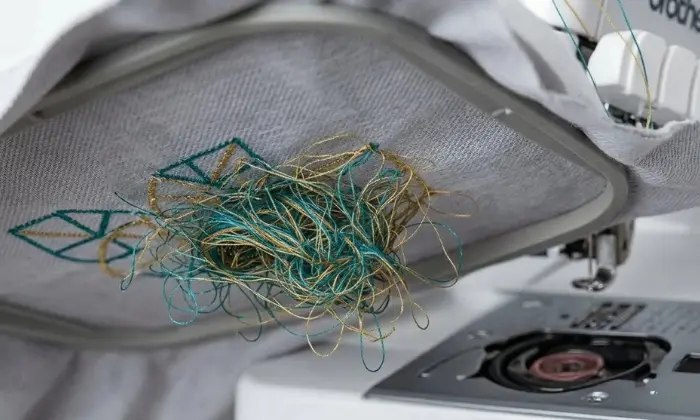 Bird nesting in machine embroidery showing tangled thread under fabric due to tension, threading, or bobbin problems. Bird nesting in machine embroidery showing tangled thread under fabric due to tension, threading, or bobbin problems.