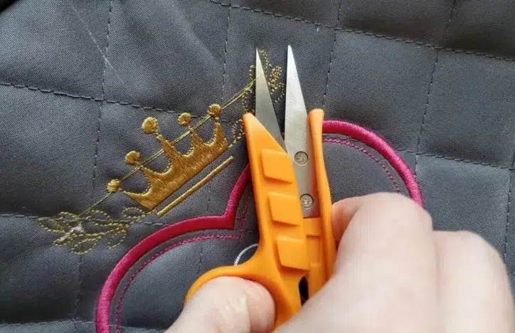 trimming jump stitches with embroidery scissors to clean loose threads from design trimming jump stitches with embroidery scissors to clean loose threads from design