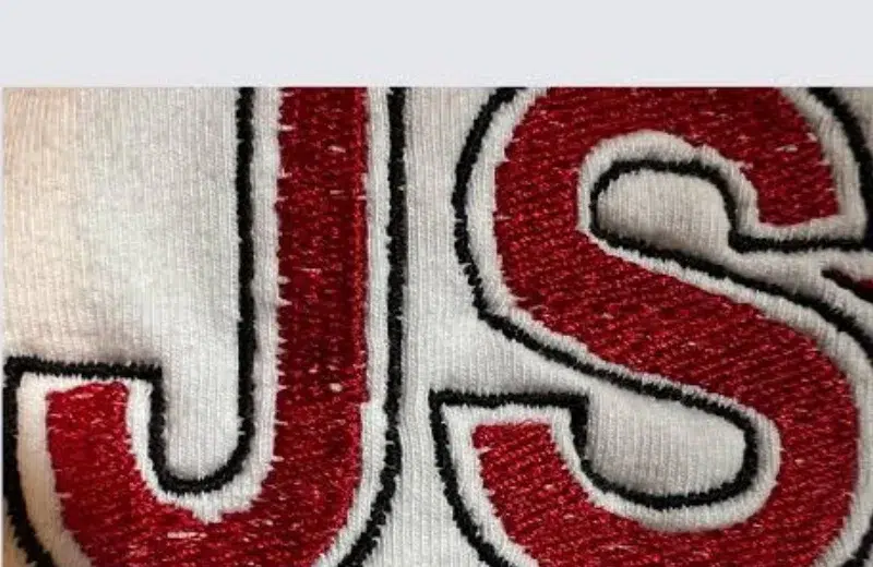 Close-up of embroidered lettering showing corner gaps, divots, and uneven stitch coverage that need proper digitizing fixes. Close-up of embroidered lettering showing corner gaps, divots, and uneven stitch coverage that need proper digitizing fixes.